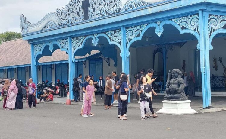 Wisatawan memanfaatkan momentum liburan untuk mengunjungi obyek wisata bersejarah Keraton Kasunanan Surakata Hadiningrat dengan foto di depan Kori Kamendungan. (Foto: Mulato Ishaan)